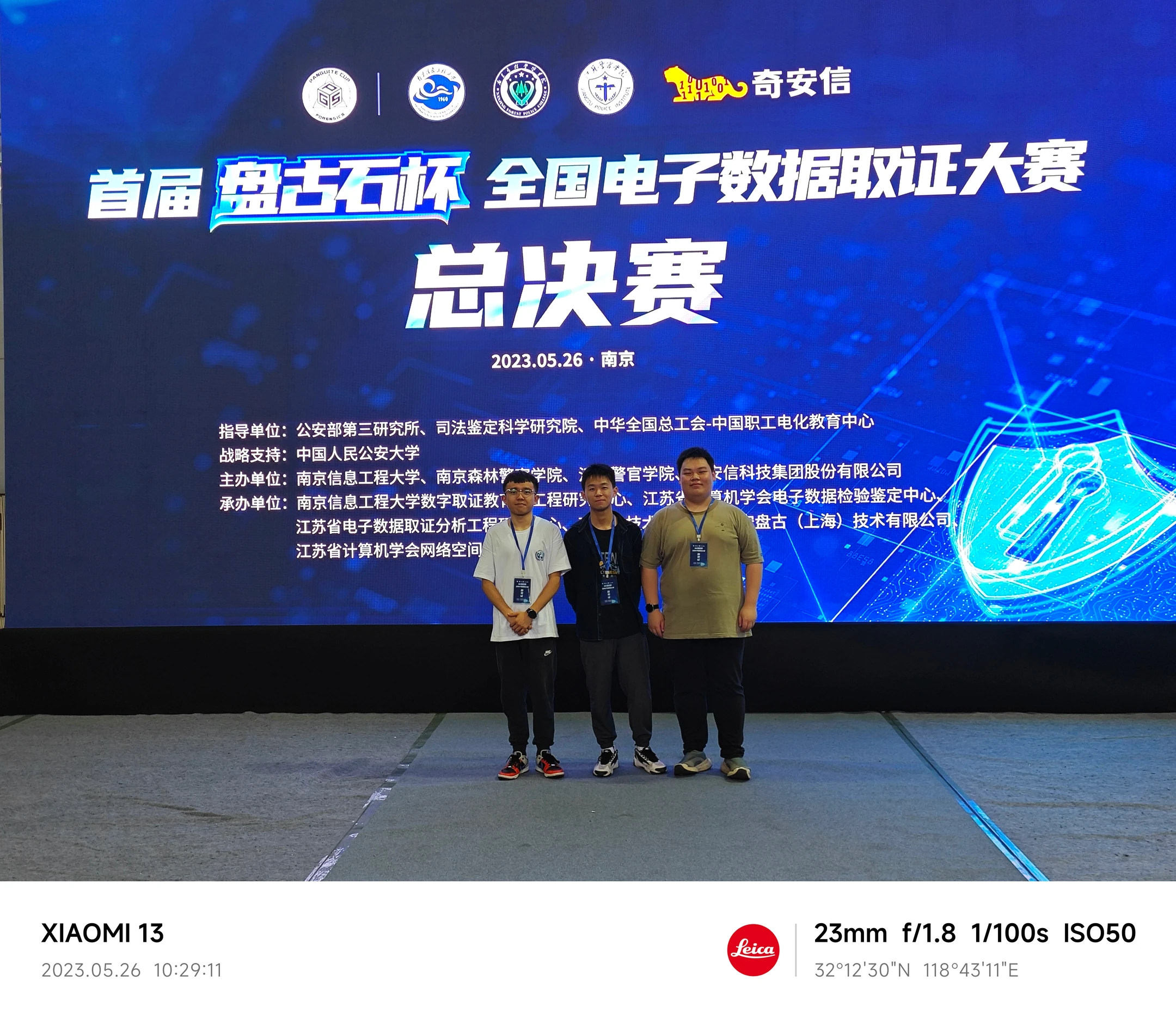 三位队员在盘古石全国电子数据取证大赛总决赛背景板前合影