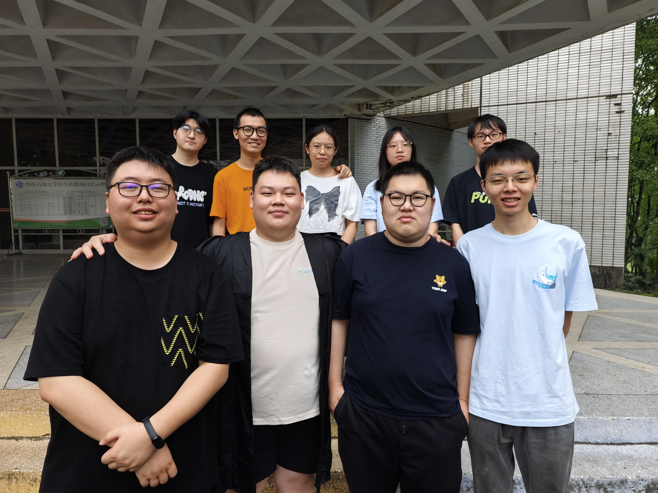 九位队员在校园建筑前合影