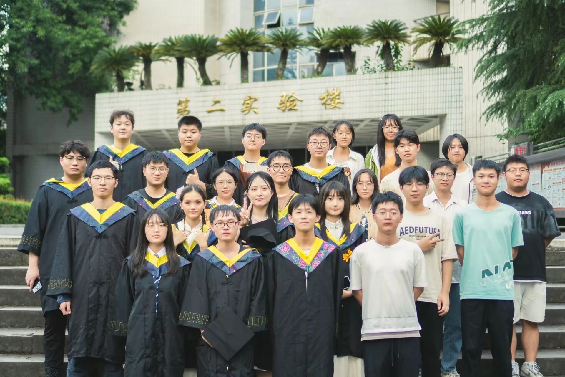 穿学位服的队员和伙伴在第二实验楼前合影